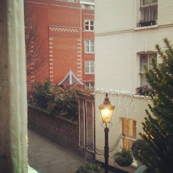 A view of an avenue through an upstairs apartment window.